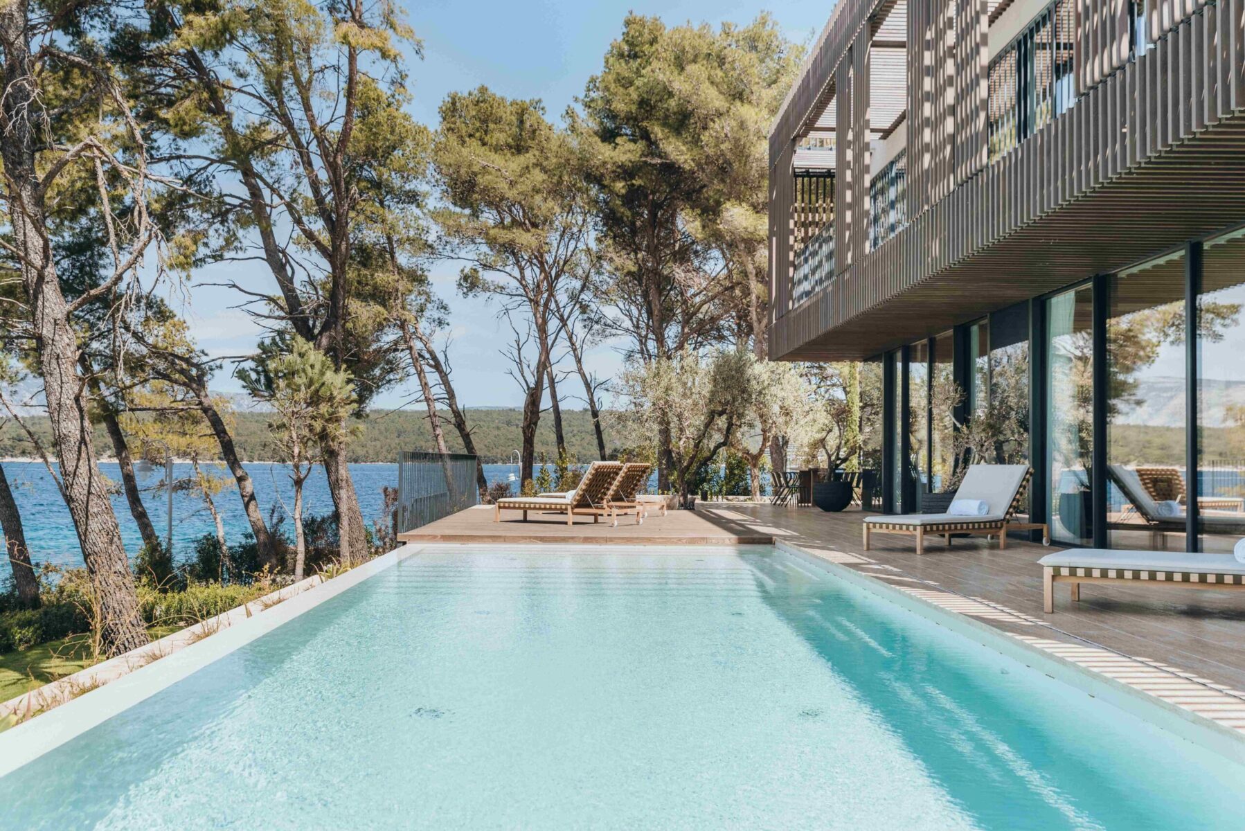DSC_5751-HDR Exterior view of a private villa at Maslina Resort, featuring modern architecture, floor-to-ceiling windows, a private pool, and views of the Adriatic Sea.